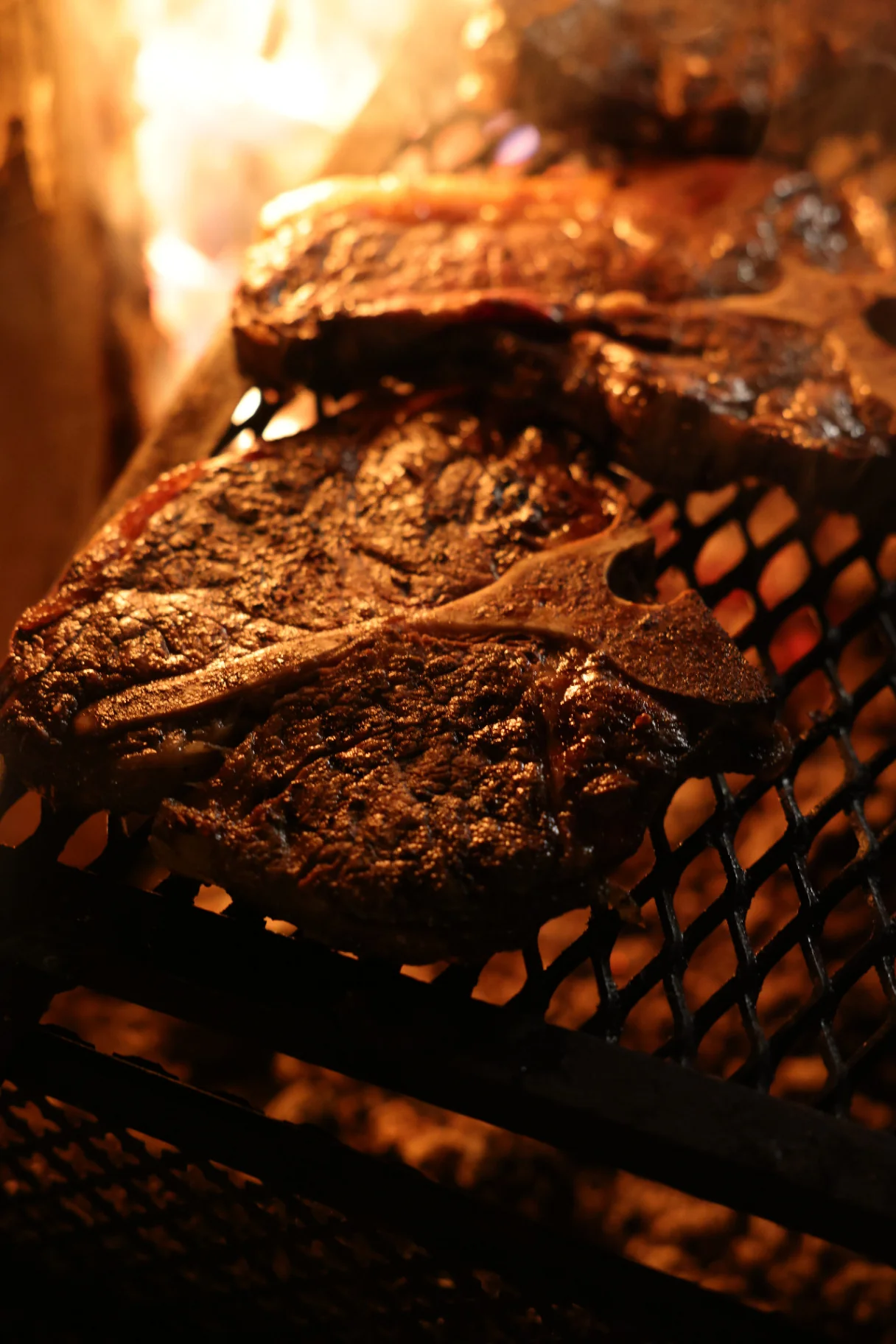 T-bone steak on the grate over glowing embers