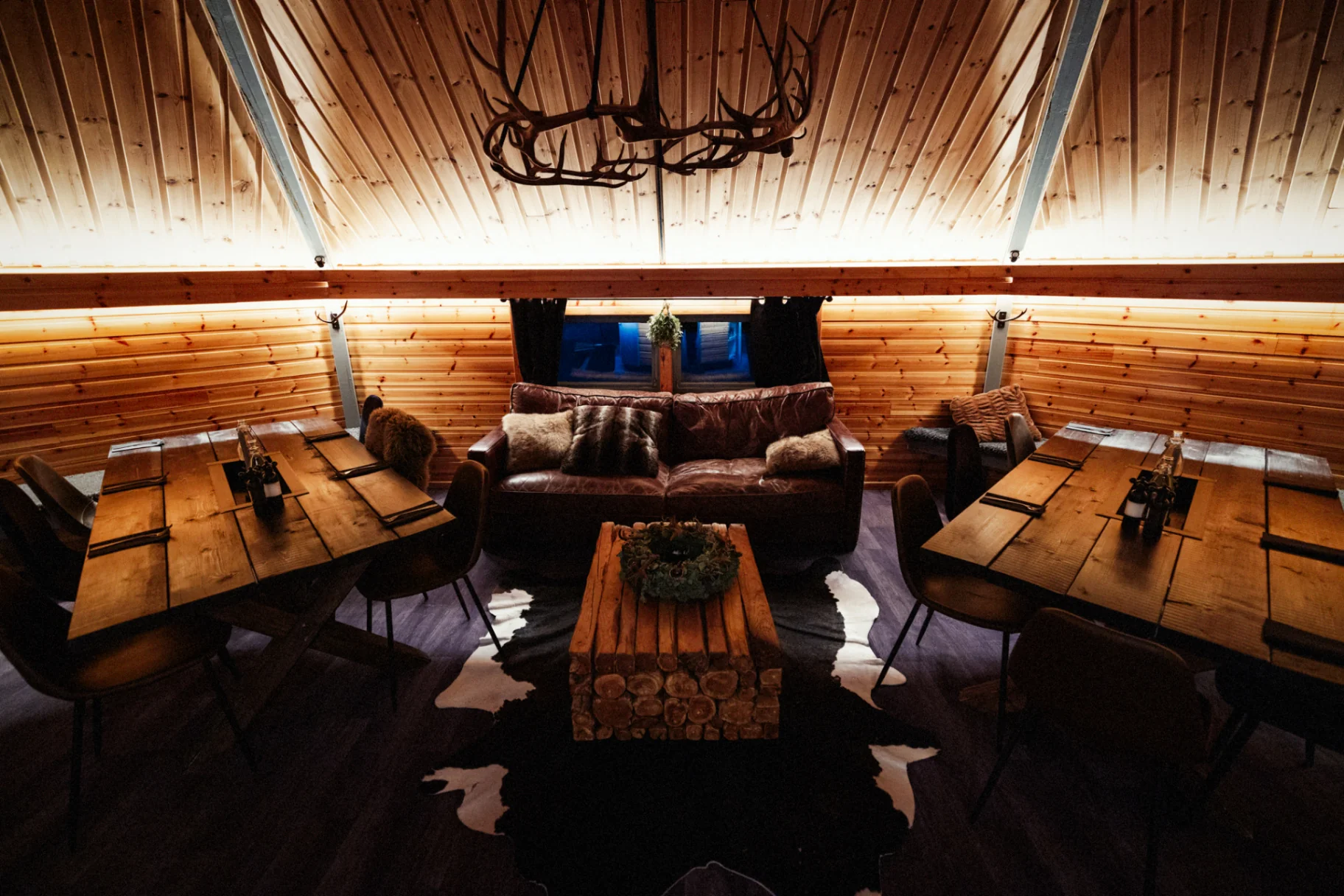 Warm wooden interior with leather sofa and antler chandelier